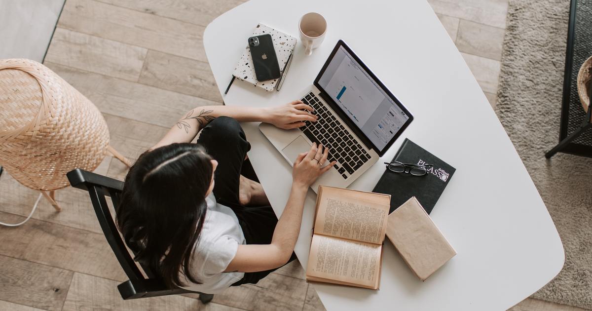 Writer typing on laptop with books on desk
