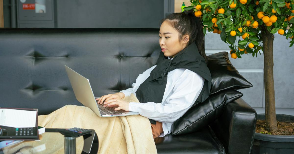 Writer sitting on a couch typing on a laptop